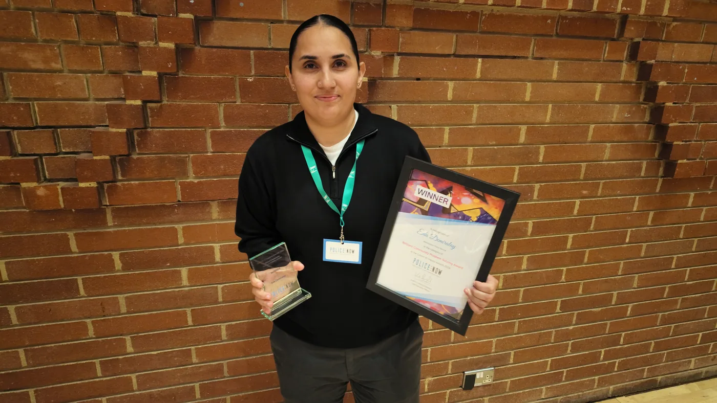 PC Eda Demiralay holding her trophy and framed winner's certificate against a brick wall